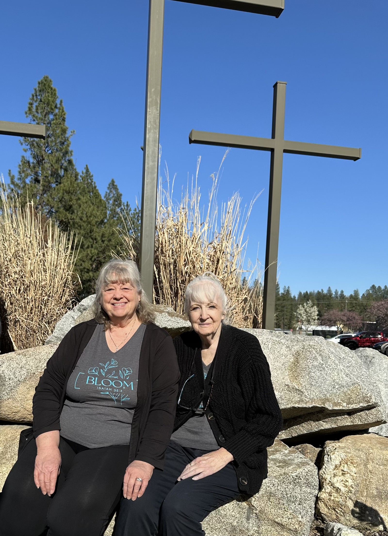 Barbara and Franny sitting on boulders with crosses behind them.